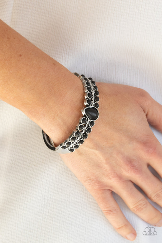 Dotted with a black stone teardrop center, rows of dainty black stones flank a thick silver bar that arcs across the wrist for an authentic look. Features a side hinged closure.  Sold as one individual bracelet.  