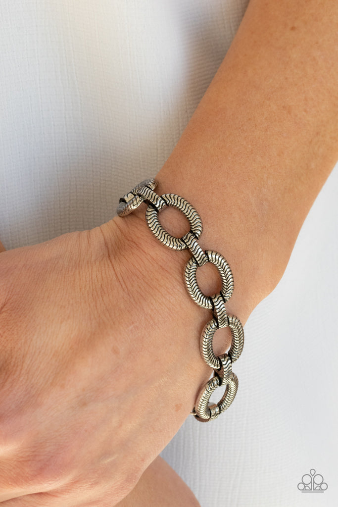 Stamped in snake chain detail, antiqued silver ovals and matching silver links interlock across the wrist for a wild industrial look. Features an adjustable clasp closure.  Sold as one individual bracelet.