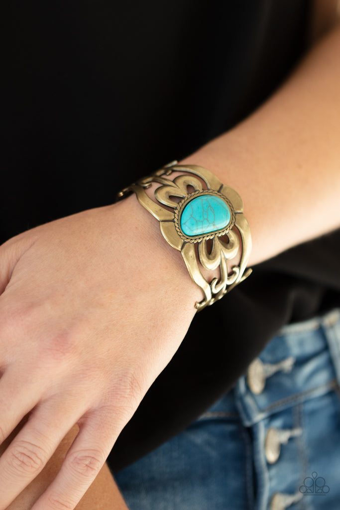 An asymmetrical turquoise stone is pressed into the center of a brass cuff layered with filigree patterns around the wrist for a rustic flair.  Sold as one individual bracelet.