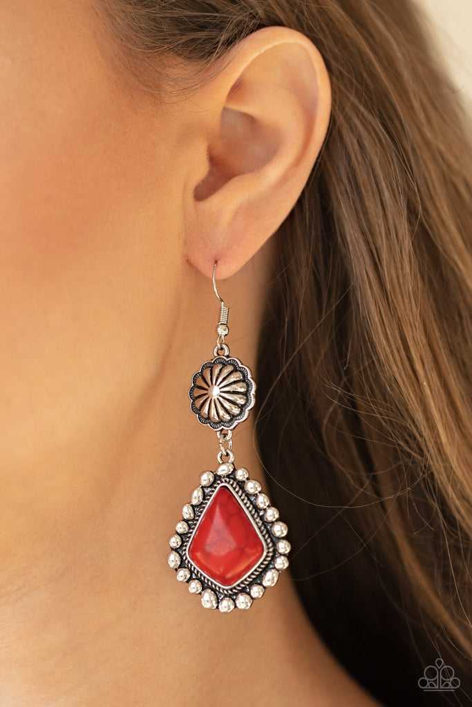 Pressed into a studded silver frame, a faceted red stone swings from the bottom of an antiqued silver floral frame for a rustic flair. Earring attaches to a standard fishhook fitting.  Sold as one pair of earrings.  