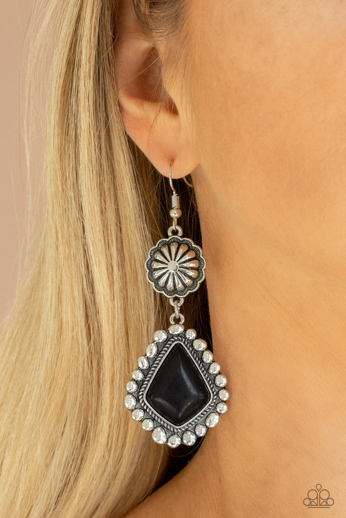 Pressed into a studded silver frame, a faceted black stone swings from the bottom of an antiqued silver floral frame for a rustic flair. Earring attaches to a standard fishhook fitting.  Sold as one pair of earrings.