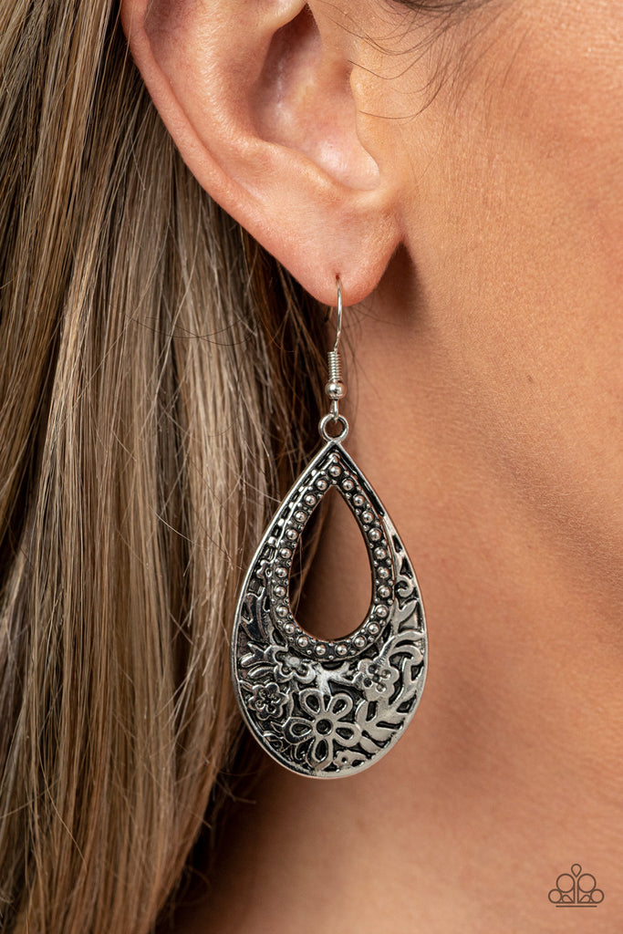 Featuring an airy studded center, the thickened bottom of an antiqued silver teardrop is embossed in a flowery pattern for a whimsical flair. Earring attaches to a standard fishhook fitting.  Sold as one pair of earrings.
