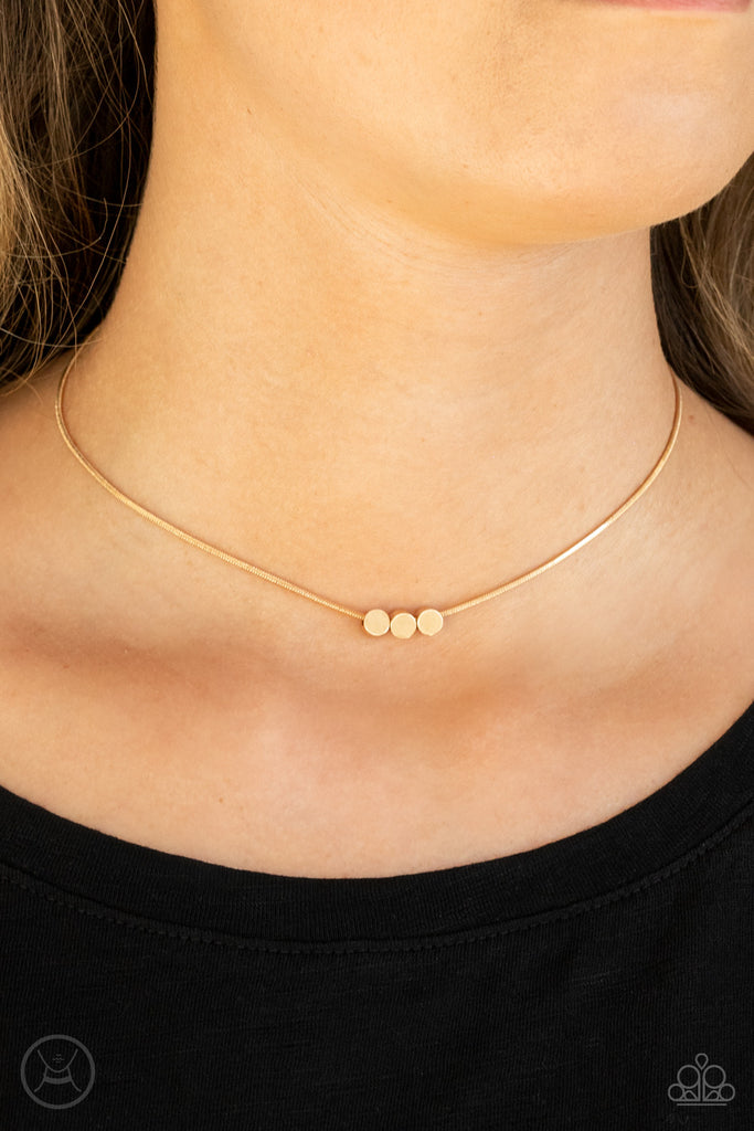 A trio of flat gold beads glide along a glistening gold snake chain around the neck, creating a dainty display. Features an adjustable clasp closure.  Sold as one individual choker necklace. Includes one pair of matching earrings.
