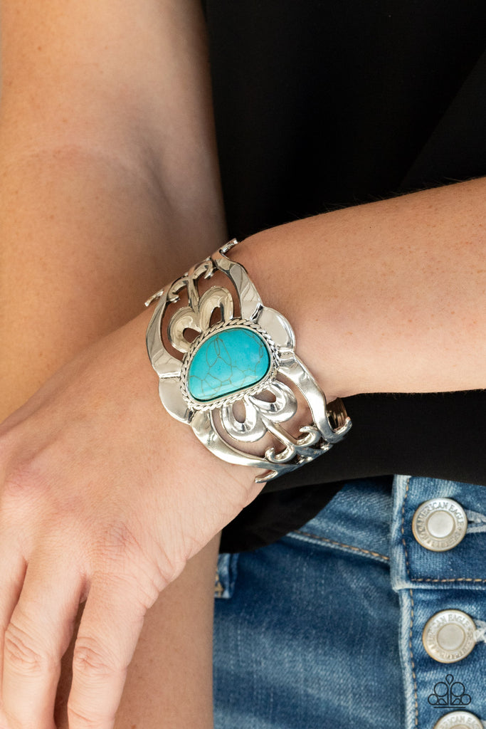An asymmetrical turquoise stone is pressed into the center of a silver cuff layered with filigree patterns around the wrist for a rustic flair.  Sold as one individual bracelet.