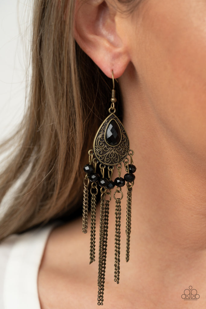 Dotted with glittery black rhinestones, antiqued brass chains stream from the bottom of a brass filigree embossed teardrop, creating a whimsical fringe. A teardrop black rhinestone dots the frame for a dazzling finish. Earring attaches to a standard fishhook fitting.  Sold as one pair of earrings.