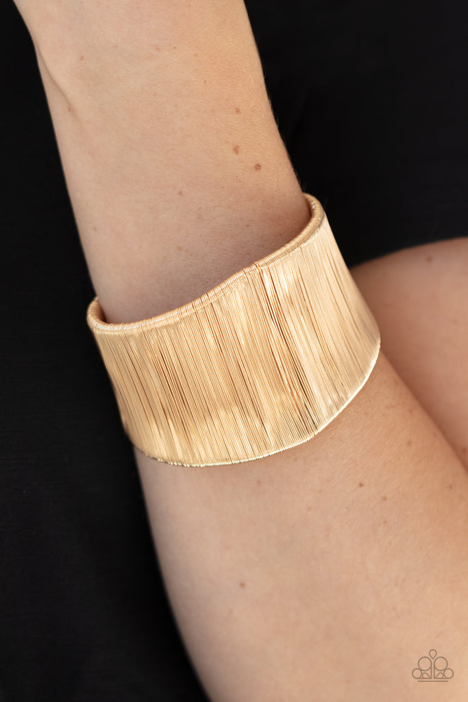 A seemingly infinite collection of shimmery gold wire wraps around the a substantial gold cuff, creating a bold industrial inspired centerpiece around the wrist.  Sold as one individual bracelet.