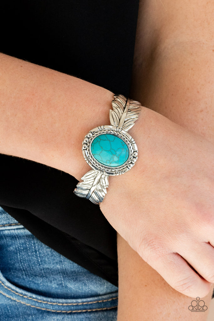 Stamped and embossed in lifelike textures, two shiny silver feathers branch out from a turquoise stone frame featuring rustic silver details. The whimsical centerpiece curls around the wrist, creating a free-spirited cuff.  Sold as one individual bracelet.