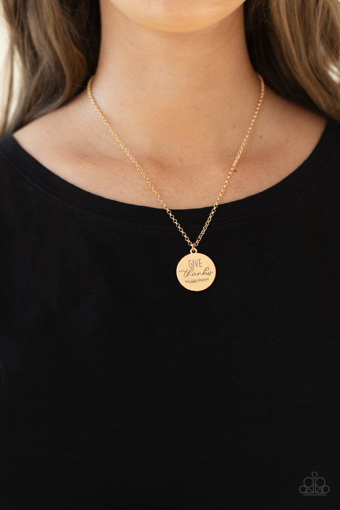 Infused with feathery accents, a shiny gold disc is stamped in the phrase, "Give Thanks," at the bottom of a shimmery gold chain. Features an adjustable clasp closure.  Sold as one individual necklace. Includes one pair of matching earrings.  