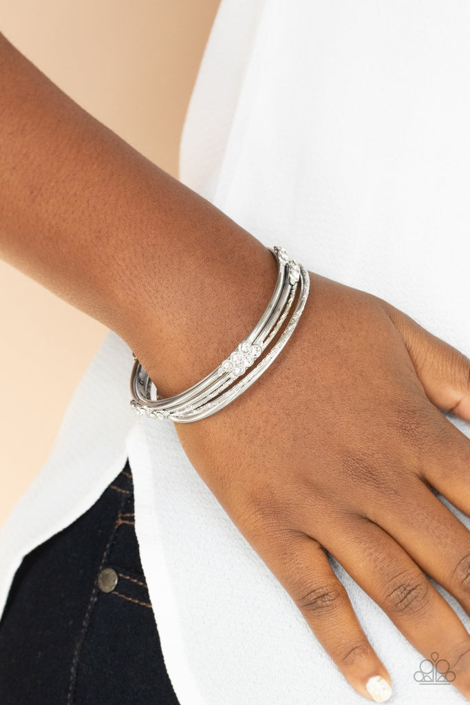 Pairs of plain, textured, and white rhinestone adorned silver bangles glide along the wrist for a sparkly look.  Sold as one set of six bracelets.  