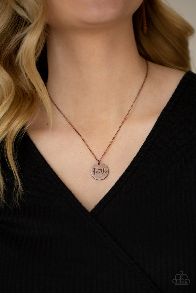 A dainty copper disc is stamped in the word, "Faith," at the bottom of a rustic copper chain, creating an inspiring pendant below the collar. Features an adjustable clasp closure.  Sold as one individual necklace. Includes one pair of matching earrings.