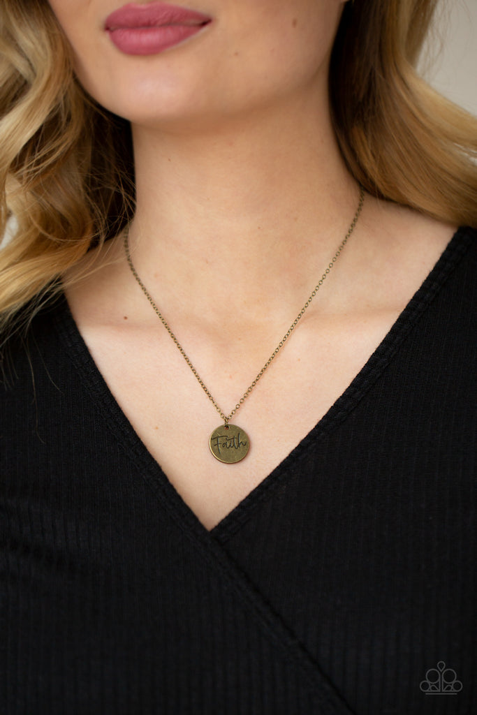 A dainty brass disc is stamped in the word, "Faith," at the bottom of a rustic brass chain, creating an inspiring pendant below the collar. Features an adjustable clasp closure.  Sold as one individual necklace. Includes one pair of matching earrings.  