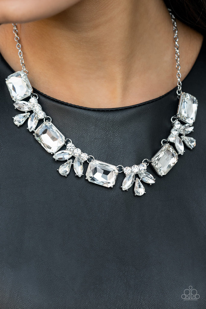 An oversized collection of white emerald cut gems and regally cut clusters of rhinestones delicately link below the collar, creating a dramatically sparkly fringe. Features an adjustable clasp closure.  Sold as one individual necklace. Includes one pair of matching earrings.  
