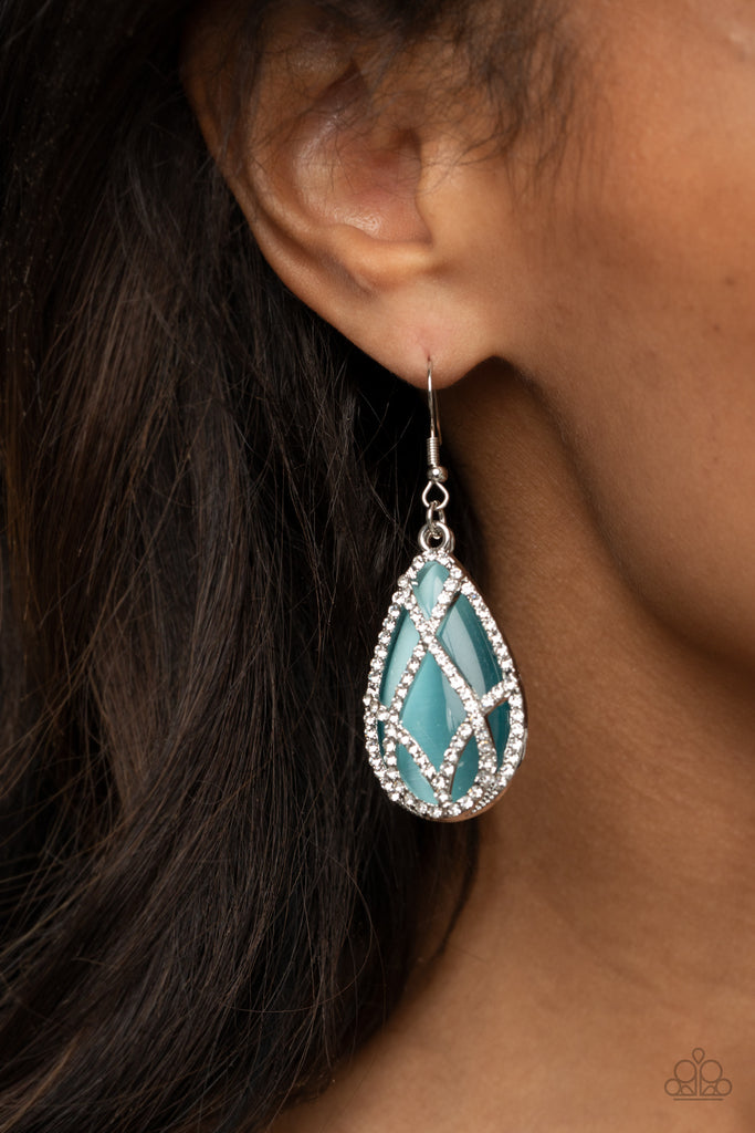 White rhinestone encrusted silver bars crisscross into a glittering beveled teardrop that delicately overlaps an oversized blue teardrop cat's eye stone, creating a luminously layered lure. Earring attaches to a standard fishhook fitting.  Sold as one pair of earrings.