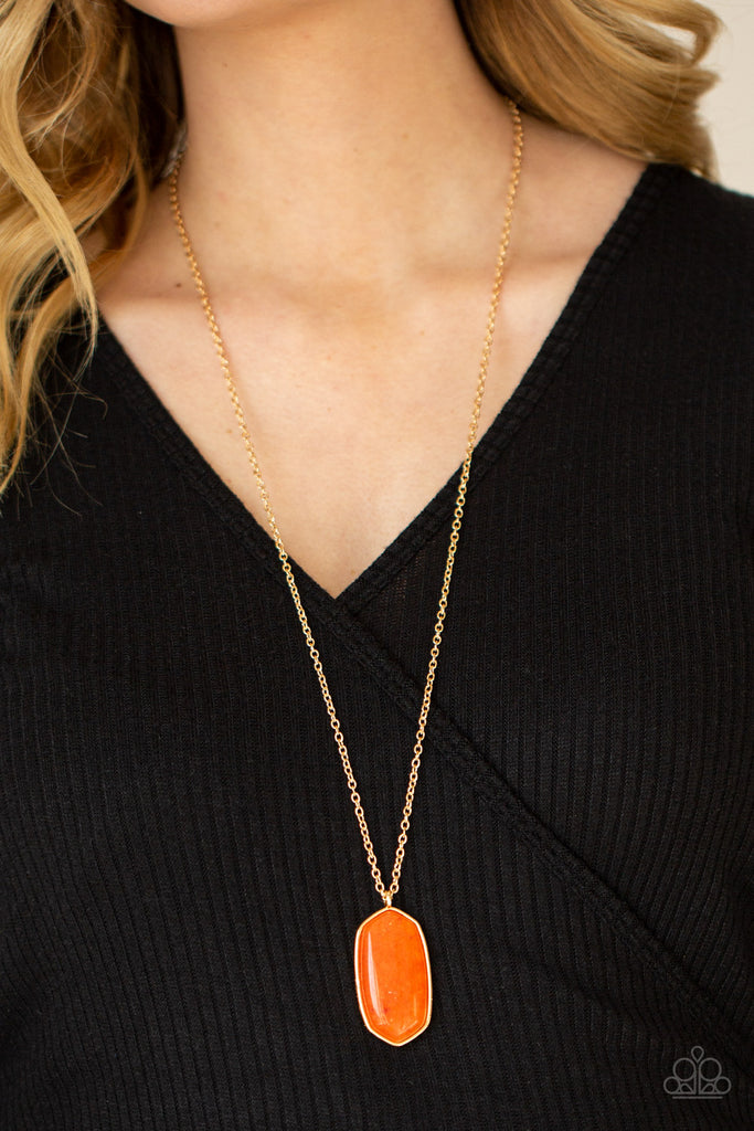 Encased in a classic gold fitting, a glassy orange stone swings from the bottom of a lengthened gold chain for an elegantly earthy look. Features an adjustable clasp closure.  Sold as one individual necklace. Includes one pair of matching earrings.