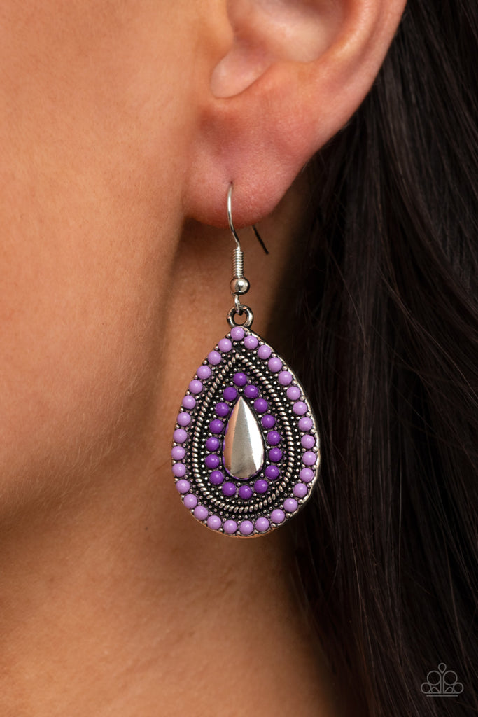The front of a studded silver teardrop frame is dotted in alternating rows of light and dark purple beads, creating a colorful lure. Earring attaches to a standard fishhook fitting.  Sold as one pair of earrings.