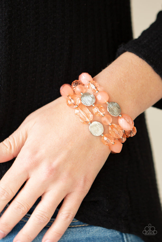 Glassy and opaque coral crystal-like beads and textured silver accents are threaded along stretchy bands around the wrist, creating mystical layers.  Sold as one set of three bracelets.