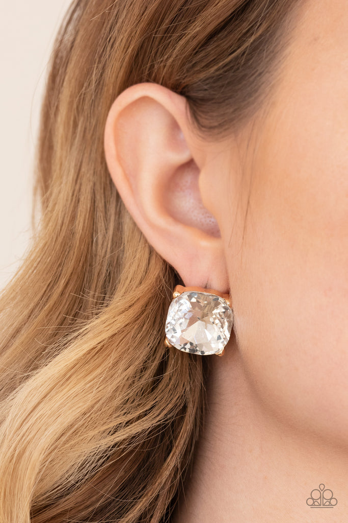 A dramatically oversized white gem is nestled atop a pronged gold frame, creating a jaw-dropping dazzle. Earring attaches to a standard post fitting.  Sold as one pair of post earrings.