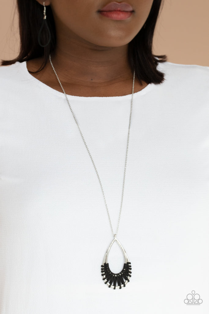 Black suede cording loops and weaves around the bottoms of a double stacked silver teardrop frame, creating an earthy pendant at the bottom of a dainty lengthened silver chain. Features an adjustable clasp closure.  Sold as one individual necklace. Includes one pair of matching earrings.