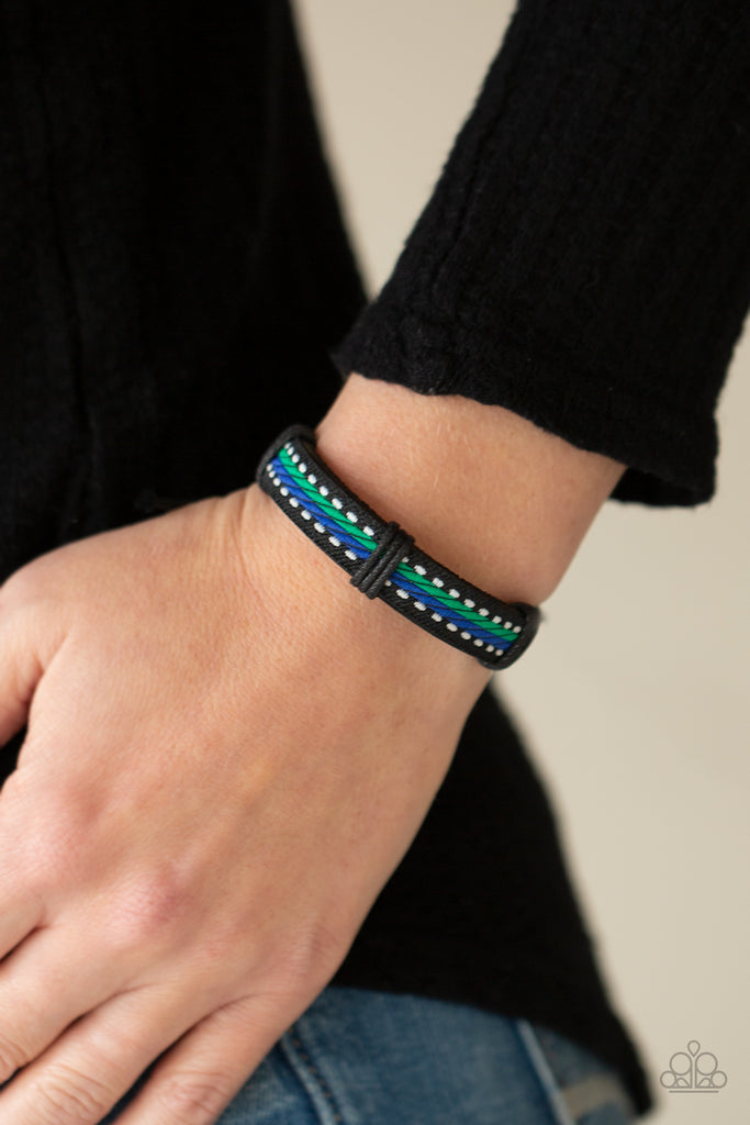 Featuring blue, green, and white thread, a decorative textile is knotted in place across the front of a dainty black leather band for an adventurous look. Features an adjustable sliding knot closure.  Sold as one individual bracelet.  