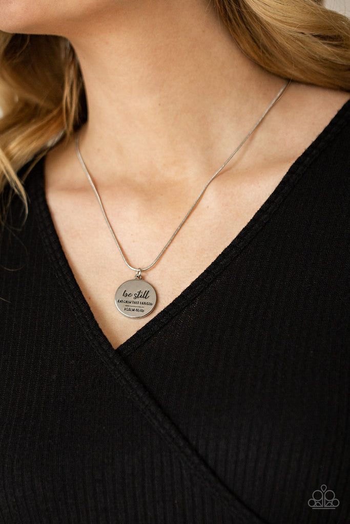 A glistening silver disc is stamped in the bible verse, "Be still and know that I am God. Psalm 16:13," creating an inspiring pendant below the collar. Features an adjustable clasp closure.  Sold as one individual necklace. Includes one pair of matching earrings.