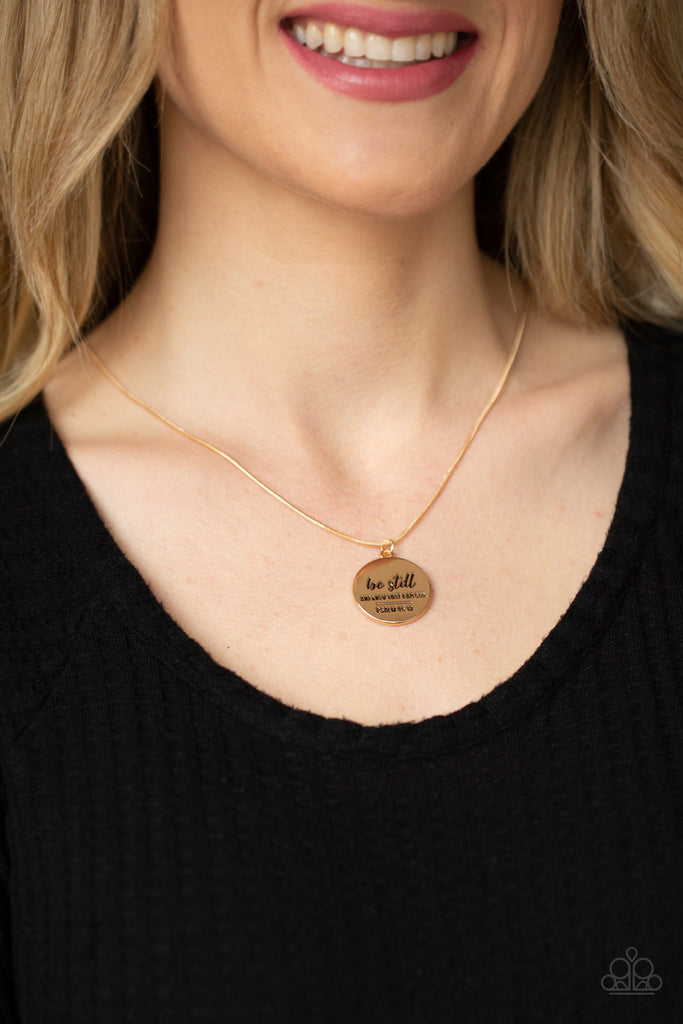 A glistening gold disc is stamped in the bible verse, "Be still and know that I am God. Psalm 46:10," creating an inspiring pendant below the collar. Features an adjustable clasp closure.  Sold as one individual necklace. Includes one pair of matching earrings.