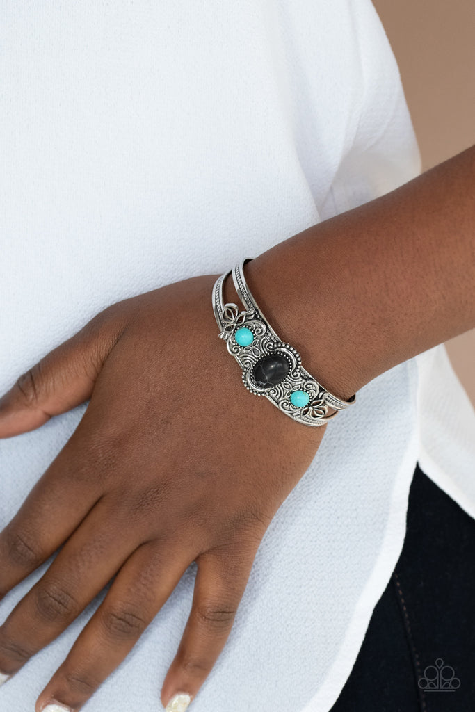 Dotted with a pair of turquoise stone beads, silver floral filigree blooms out from an oval black stone centerpiece atop a studded silver cuff.  Sold as one individual bracelet.