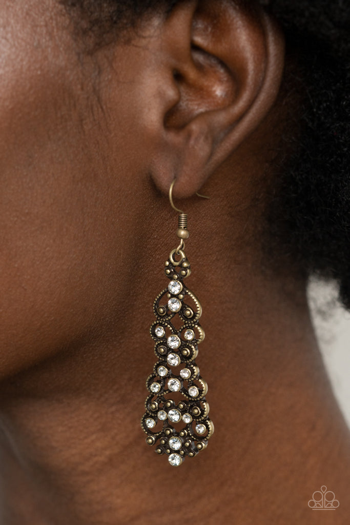 Sporadically dotted in glassy white rhinestones, studded brass filigree delicately whirls into a stacked lure for an elegant display. Earring attaches to a standard fishhook fitting.  Sold as one pair of earrings.