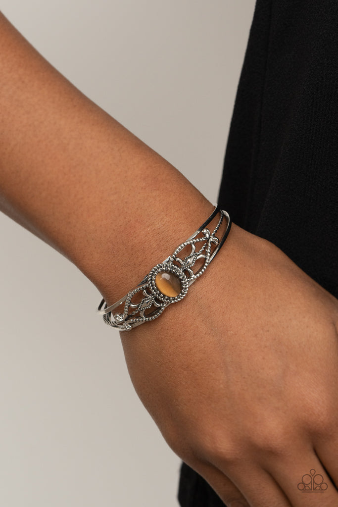 A frame of textured silver filigree whirls around a glowing brown cat's eye stone, creating a decorative centerpiece atop an ornately layered silver cuff.  Sold as one individual bracelet.  