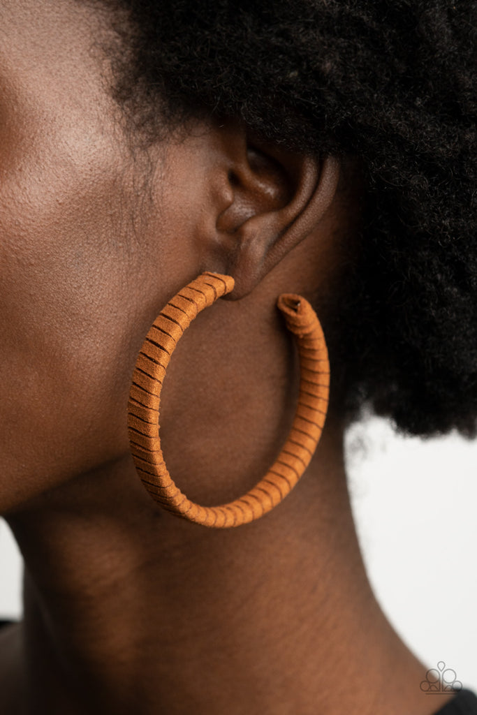 Tan suede cording wraps around an oversized hoop, creating an earthy pop of color. Earring attaches to a standard post fitting. Hoop measures approximately 2 1/4" in diameter.  Sold as one pair of hoop earrings.