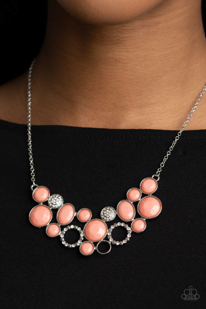 A mismatched collection of faceted coral beaded frames and white rhinestone embellished accents delicately connect into a bubbly clustered pendant below the collar, creating a colorful statement piece. Features an adjustable clasp closure.  Sold as one individual necklace. Includes one pair of matching earrings.