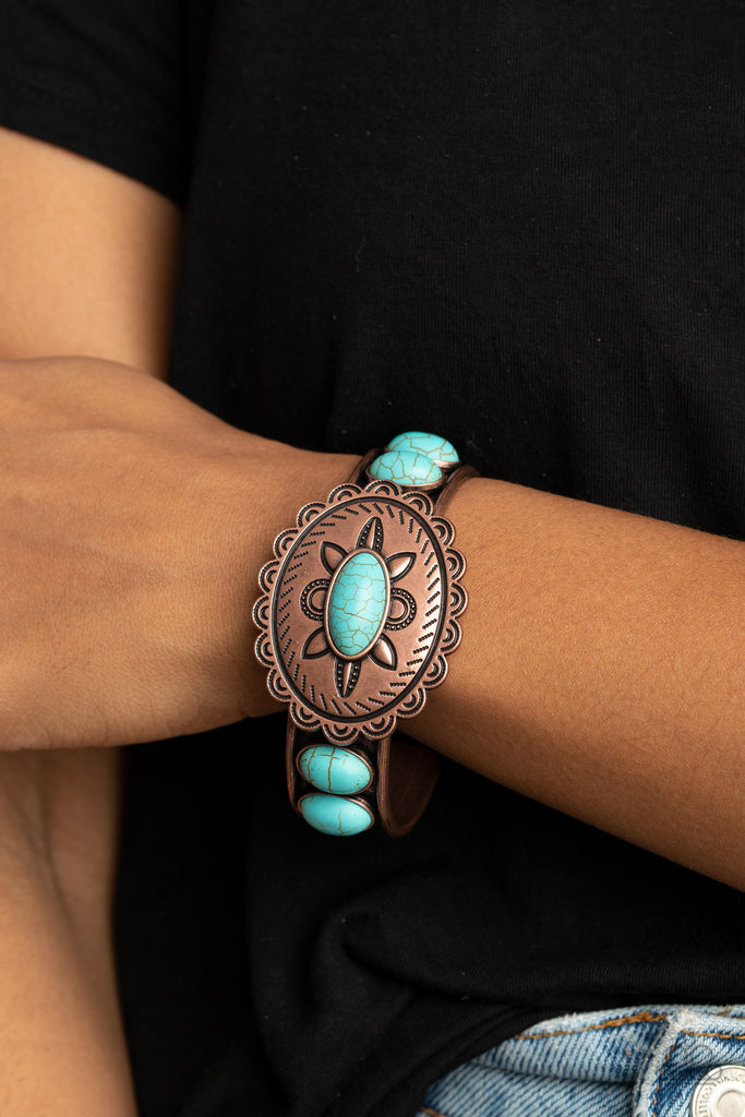 Dotted with a refreshing turquoise stone, a floral stamped scalloped copper frame sits atop a turquoise studded copper cuff, creating a southwestern inspired buckle atop the wrist.  Sold as one individual bracelet.