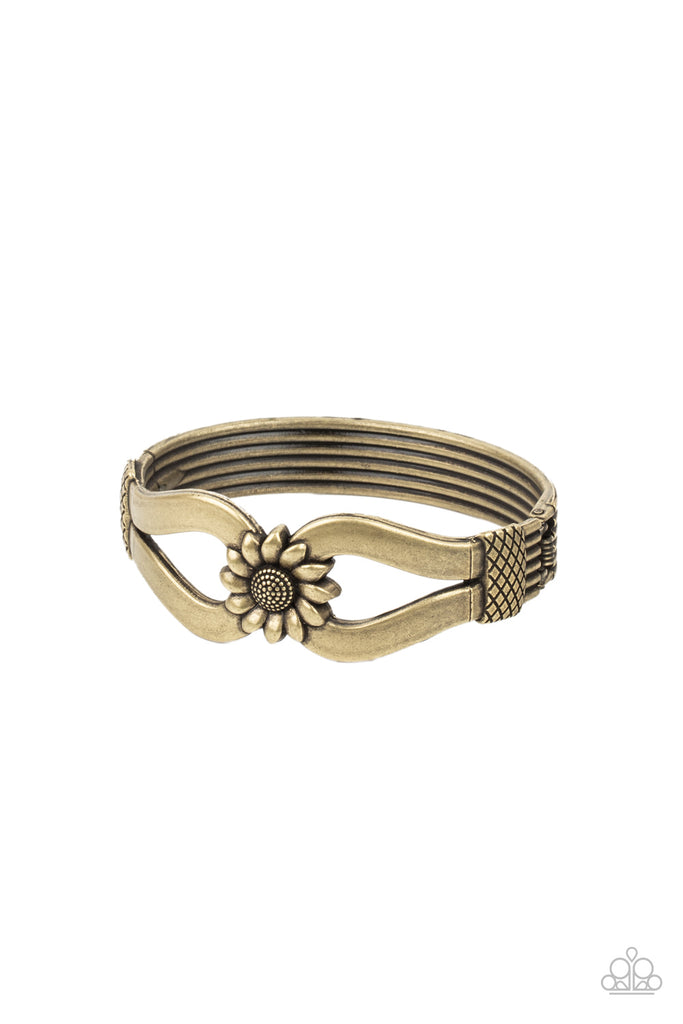 let-a-hundred-sunflowers-bloom-brass  Antiqued brass ribbons loop out from a decorative brass sunflower that attaches to a ribbed brass frame, creating a cuff-like bangle around the wrist. Features a hinged closure.  Sold as one individual bracelet.