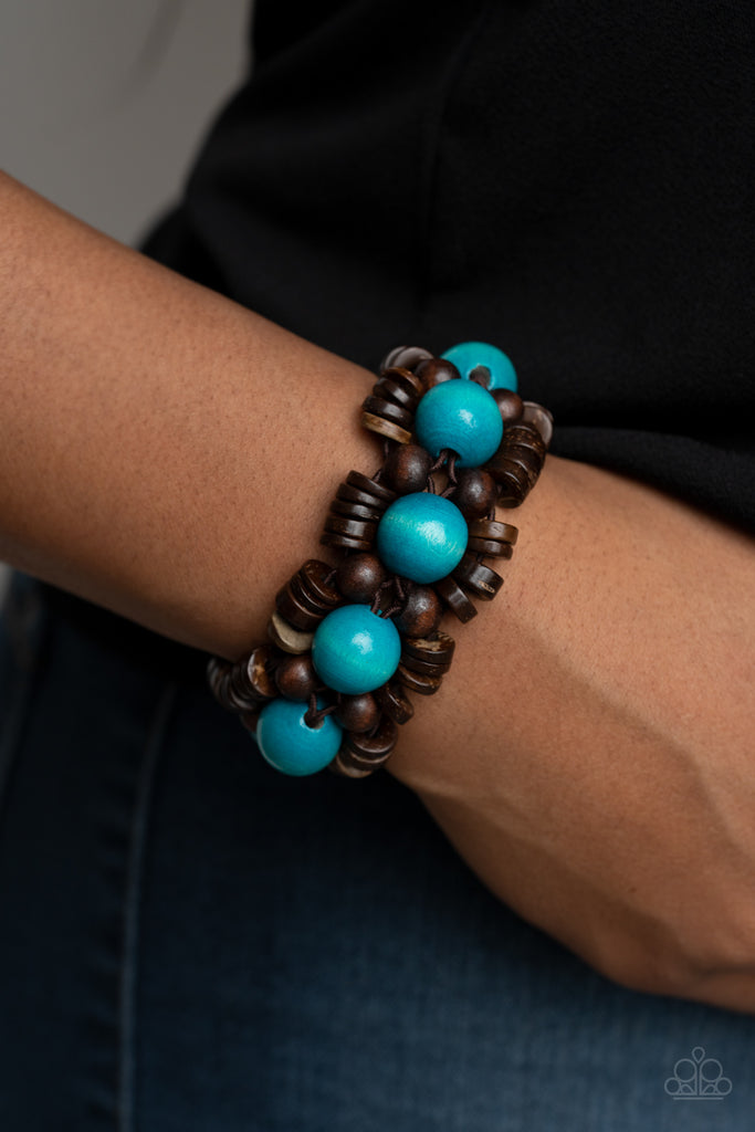 Oversized blue wooden beads, rustic brown wooden beads, and dainty wooden discs are ornately threaded along braided stretchy bands around the wrist, creating a summery centerpiece.  Sold as one individual bracelet.  