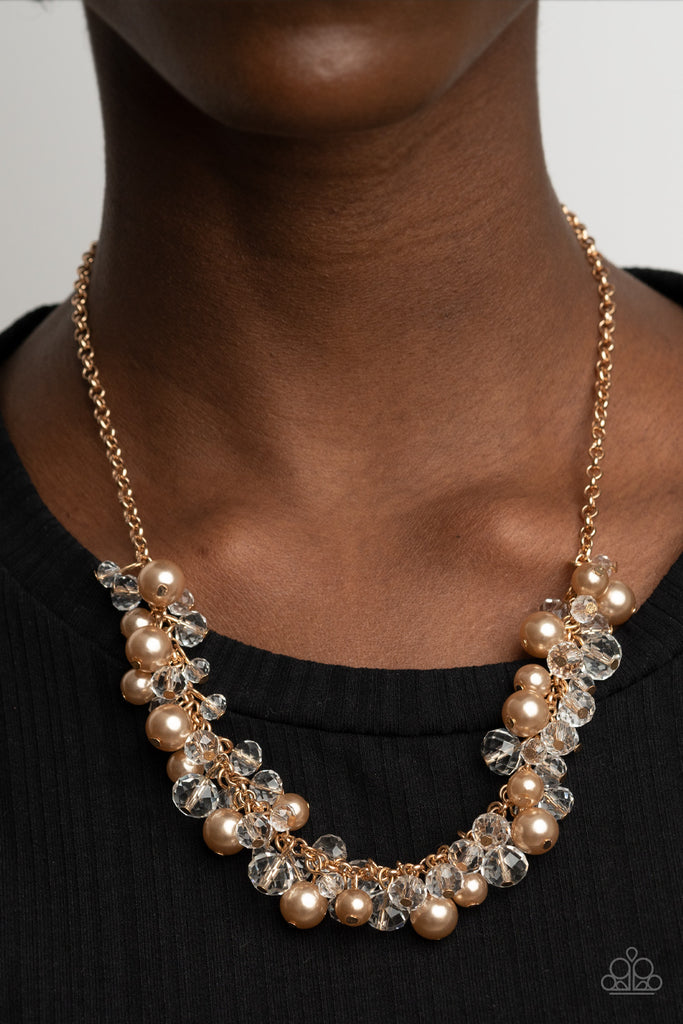 A royal collection of golden brown pearls and glassy crystal-like beads swing from the bottom of a dainty gold chain, creating a glamorously clustered fringe below the collar. Features an adjustable clasp closure.  Sold as one individual necklace. Includes one pair of matching earrings.