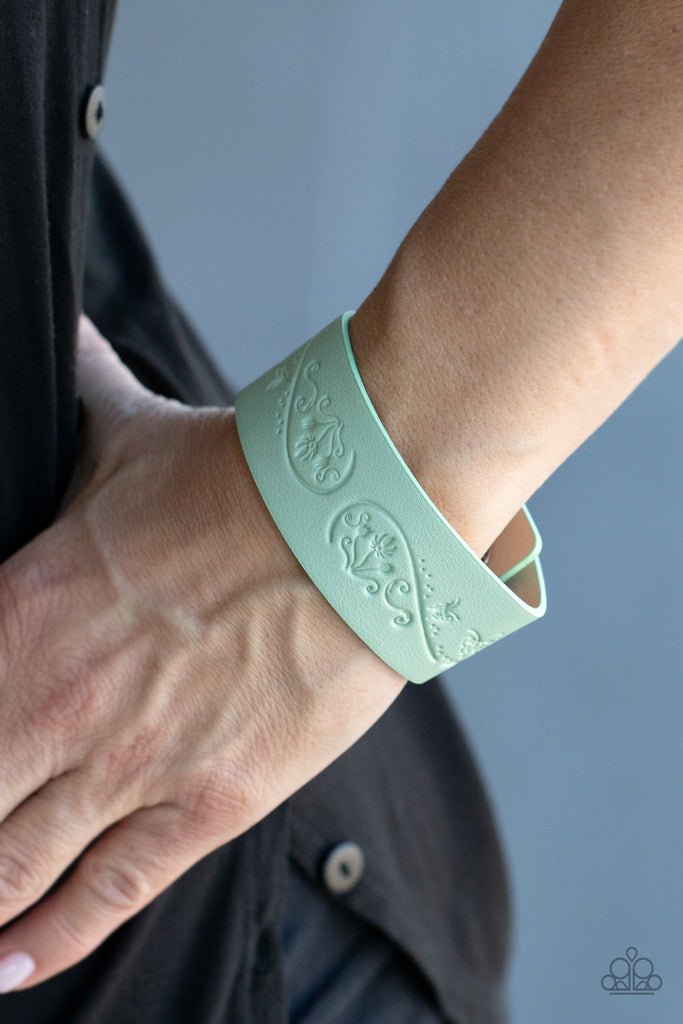 The front of a Green Ash leather band is stamped in a decorative butterfly and flower pattern, creating a whimsical display around the wrist. Features an adjustable snap closure.  Sold as one individual bracelet.