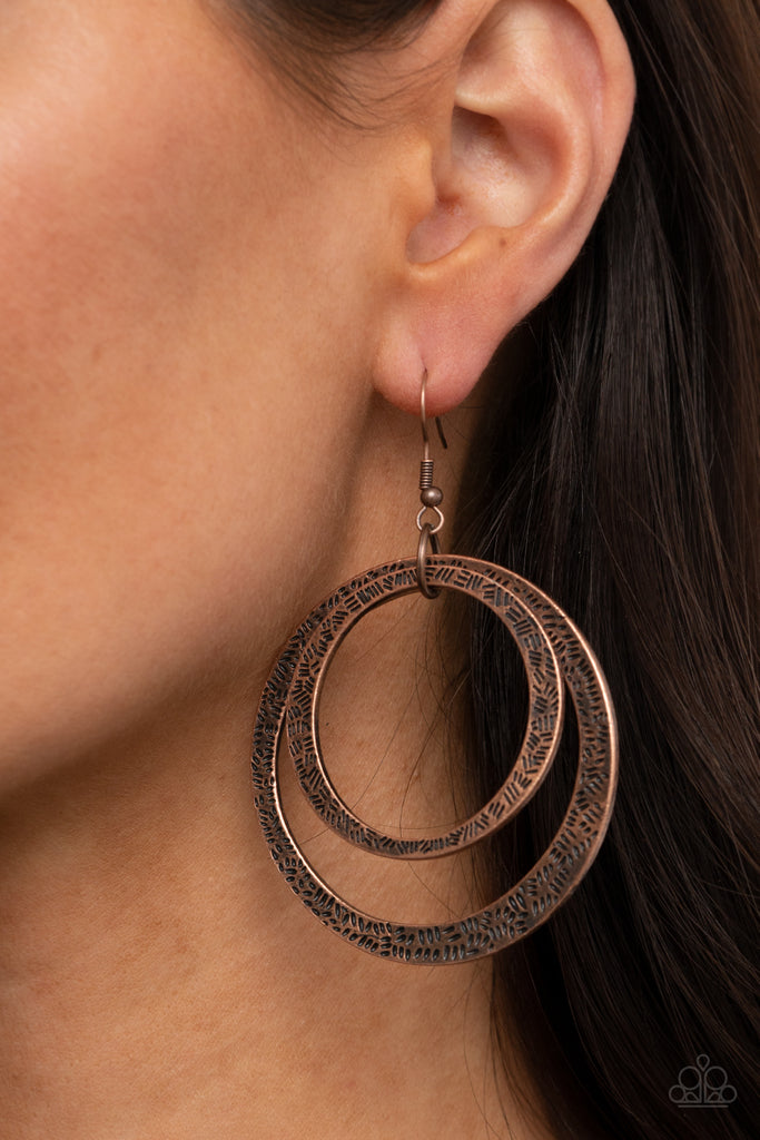 Stamped in tactile linear patterns, two asymmetrical copper rings link into a rustic hoop. Earring attaches to a standard fishhook fitting.  Sold as one pair of earrings.