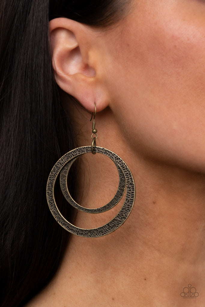 Stamped with tactile linear patterns, two asymmetrical brass rings link into a rustic hoop. Earring attaches to a standard fishhook fitting.  Sold as one pair of earrings.