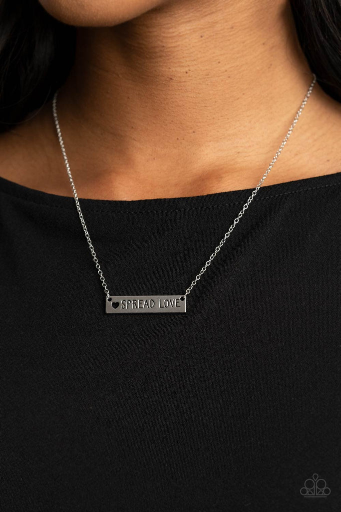 Featuring a dainty heart cutout, a shiny silver plate is stamped in the phrase, "Spread Love," creating an inspirational phrase below the collar. Features an adjustable clasp closure.  Sold as one individual necklace. Includes one pair of matching earrings.  