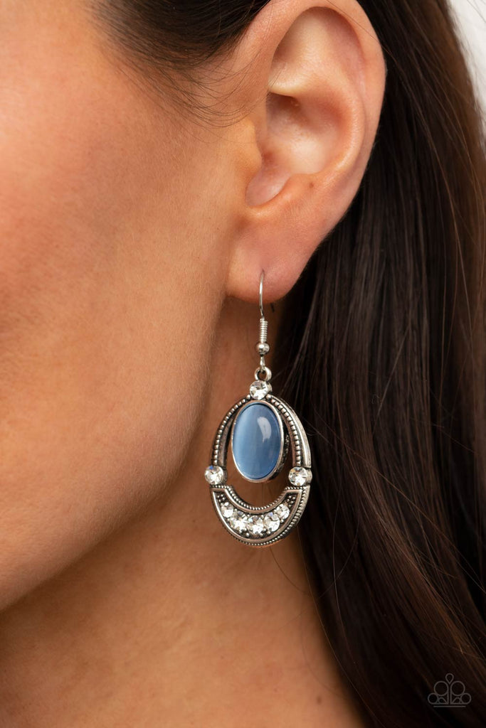 A glowing blue cat's eye stone attaches to the top of a studded silver frame. The bottom of the oval is encrusted in glassy white rhinestones, creating a whimsical display. Earring attaches to a standard fishhook fitting.  Sold as one pair of earrings.