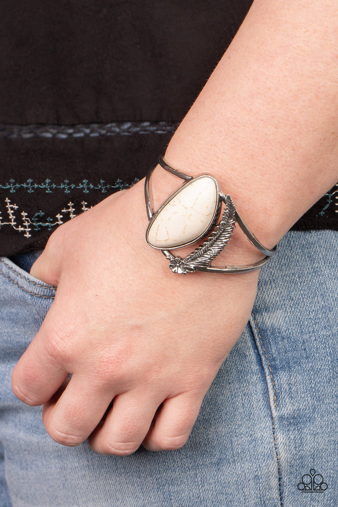 Dotted with a dainty silver flower, a lifelike silver feather charm curves around an asymmetrical white stone centerpiece atop an airy silver cuff.  Sold as one individual bracelet.  