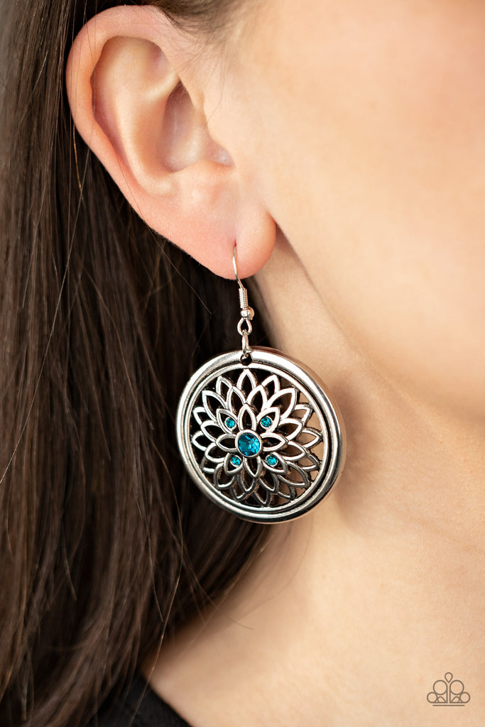 Dotted with a glittery blue rhinestone center, airy silver petals bloom across the front of a rustic silver hoop, creating a sparkly medallion-like frame. Earring attaches to a standard fishhook fitting.  Sold as one pair of earrings.