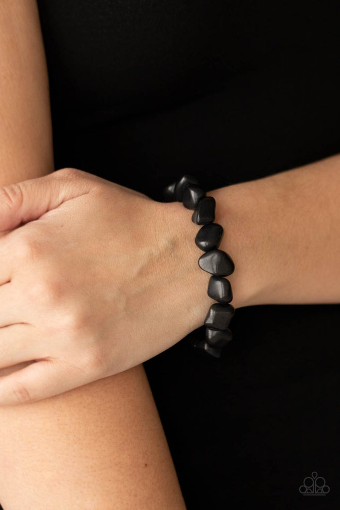 A collection of imperfect black stones are threaded along an invisible wire around the wrist, creating an earthy centerpiece. Features an adjustable clasp closure.  Sold as one individual bracelet.