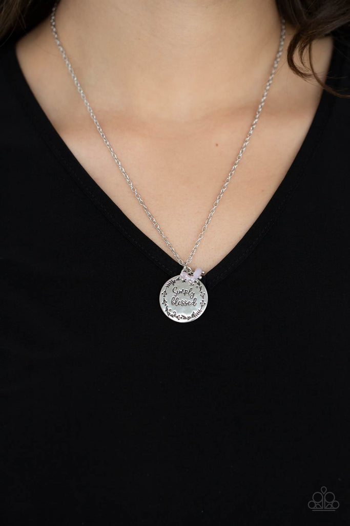 Bordered in a leafy pattern, a shiny silver disc is stamped with the phrase, "Simply Blessed," joins a dainty cluster of iridescent and opaque pink crystal-like beads at the bottom of a chain, creating an inspirational pendant below the collar. Features an adjustable clasp closure.  Sold as one individual necklace. Includes one pair of matching earrings.  