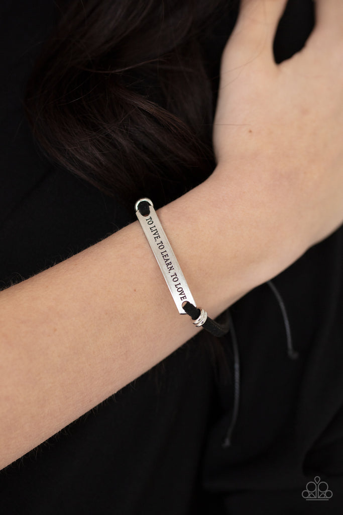 Infused with pairs of silver rings, a silver plate stamped in the phrase, "To Live, To Learn, To Love," is knotted in place around the wrist by black suede bands for an inspirational look. Features an adjustable sliding knot closure.  Sold as one individual bracelet.