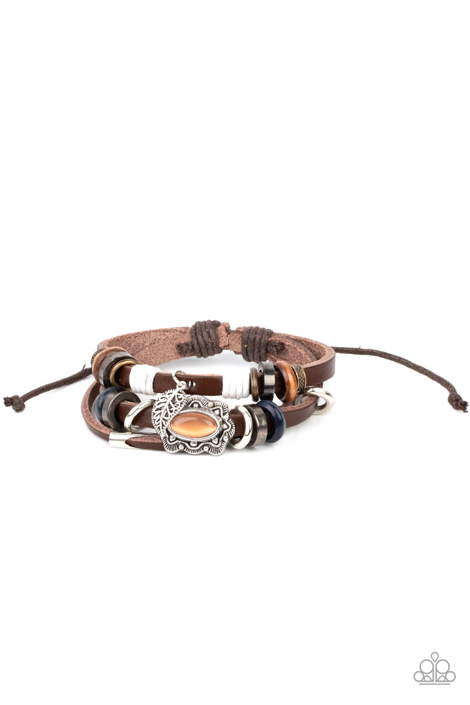 Infused with a scalloped orange cat's eye stone centerpiece, three layered leather bands are embellished with a mismatched collection of wooden and metallic rings for a seasonal finish. Features an adjustable sliding knot closure.  Sold as one individual bracelet.