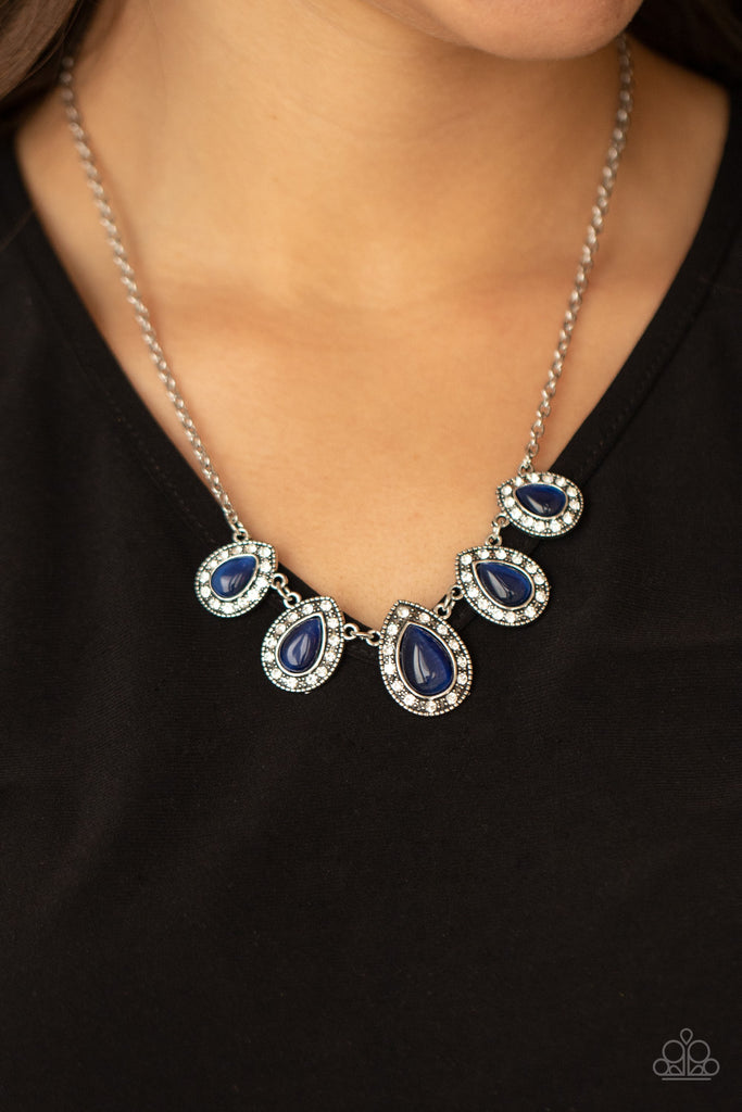 Bordered in glassy white rhinestones, glowing blue cat's eye stone frames delicately increase in size as they link below the collar, creating an enchanting display. Features an adjustable clasp closure.  Sold as one individual necklace. Includes one pair of matching earrings.