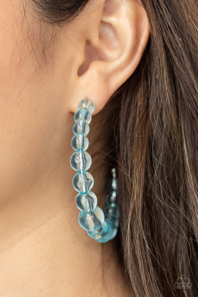 Gradually increasing in size at the center, a glassy collection of Cerulean beads are threaded along an oversized hoop for a bubbly effect. Earring attaches to a standard post fitting. Hoop measures approximately 2 1/2" in diameter.  Sold as one pair of hoop earrings.