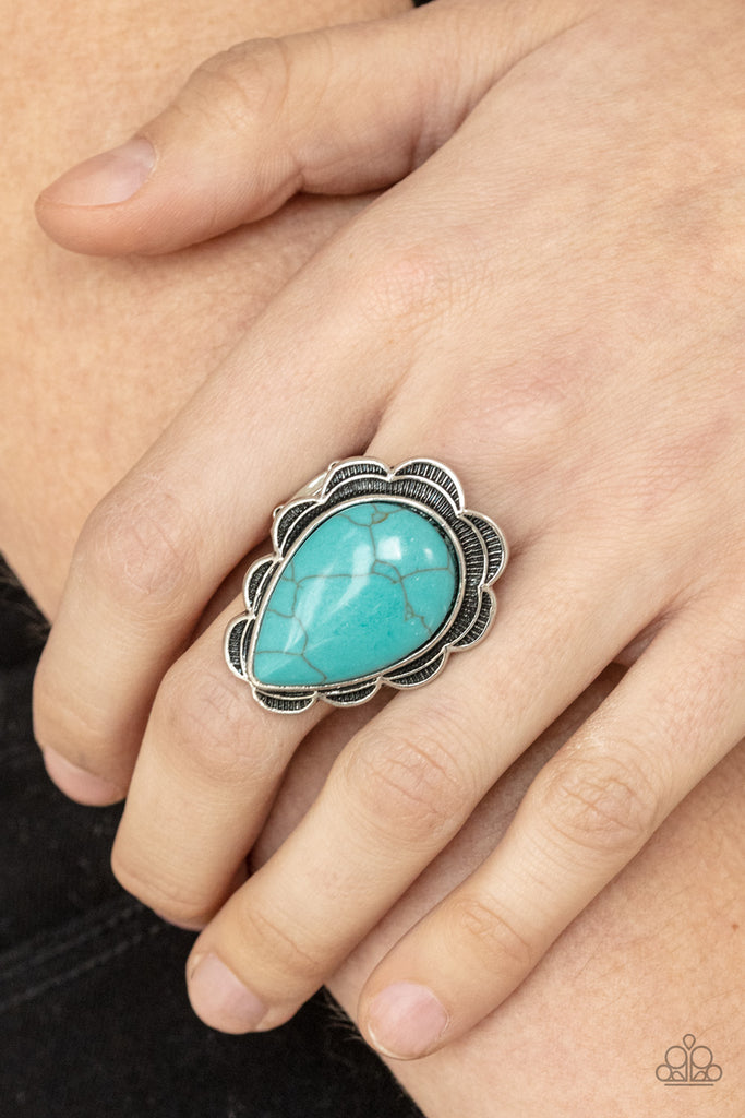 A dramatically oversized blue turquoise teardrop is nestled inside decorative silver petals, creating a colorfully rustic centerpiece atop the finger. Features a stretchy band for a flexible fit.  Sold as one individual ring.