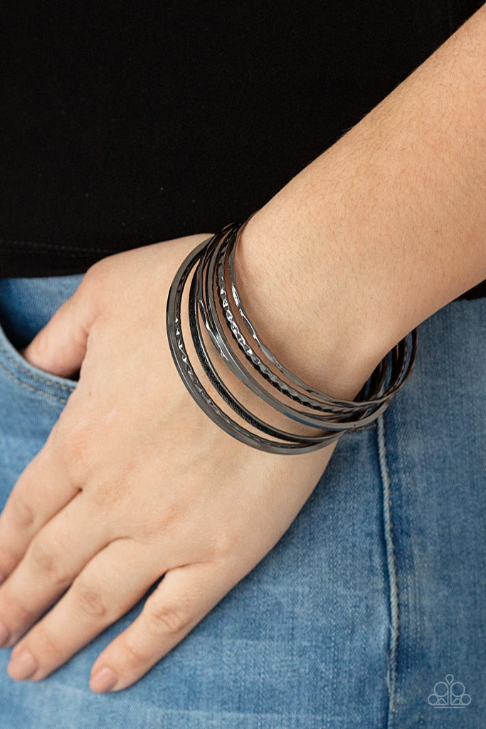 Varying in hammered, diamond-cut, and shiny finishes, a collection of mismatched gunmetal bangles stack across the wrist for an intense industrial look.  Sold as one set of seven bracelets.