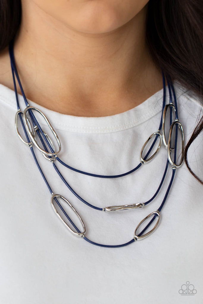 An asymmetrical collection of hammered silver ovals are fitted in place along three rows of shiny blue cords, creating an edgy display below the collar. Features an adjustable clasp closure.  Sold as one individual necklace. Includes one pair of matching earrings.